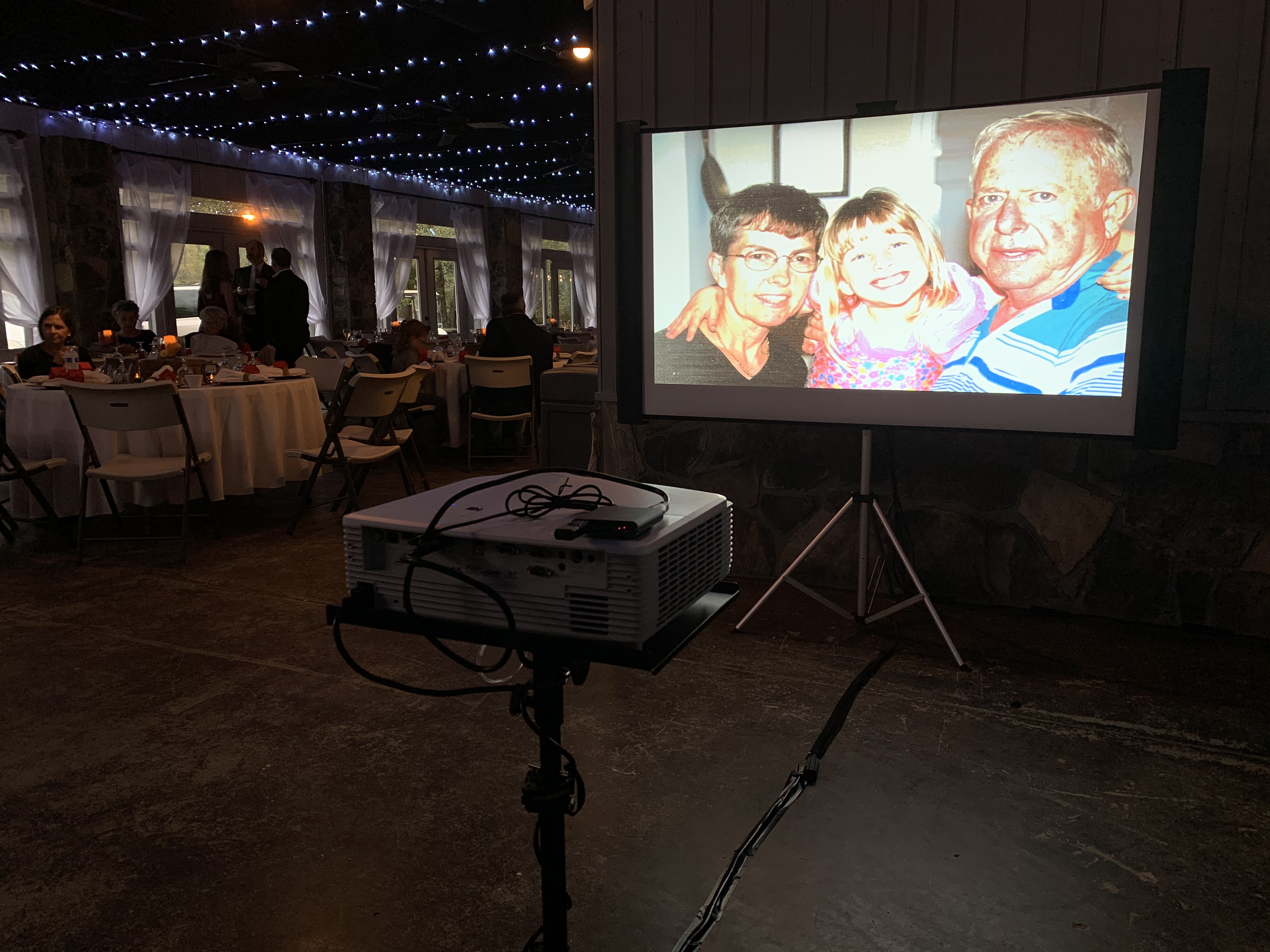 Projector and screen showing a family slideshow during dinner